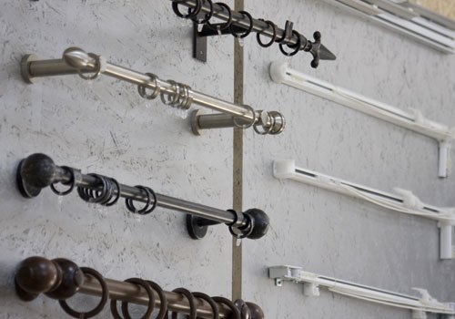Una parete con bastoni per tende in metallo e legno, anelli e binari