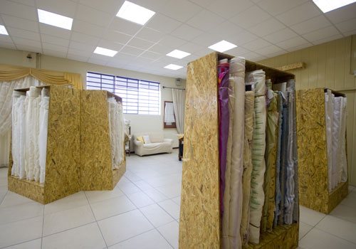 Lo spaccio: espositori in legno con i rotoli di tessuto per tende