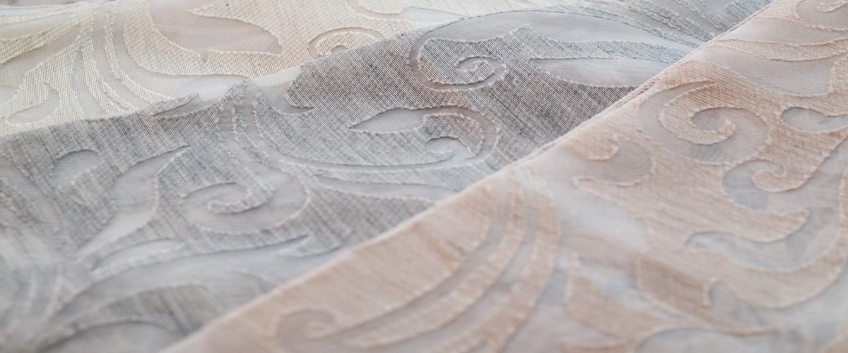 Un tessuto jacquard dai disegni floreali, nei toni del grigio e del rosa